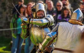 Two re-enactors dressed in knights clothing in front of crowd at an event